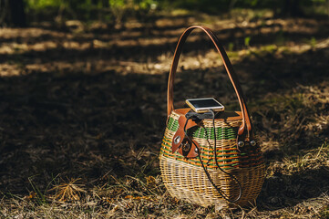 Mock up of a smartphone with charging Power Bank on a basket in the forest. Concept on the theme of...