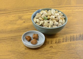 Pistachio toffee candy in candy dish with pistachio nuts in shells in ceramic bowl