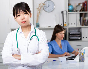 Portrait of young smiling female asian doctor meeting patient in medical office