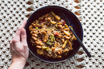 vegan stir fry with mixed vegetables and bamboo shoots topped white beans and vermicelli noodles, healthy plant-based food