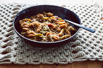 vegan stir fry with mixed vegetables and bamboo shoots topped white beans and vermicelli noodles, healthy plant-based food