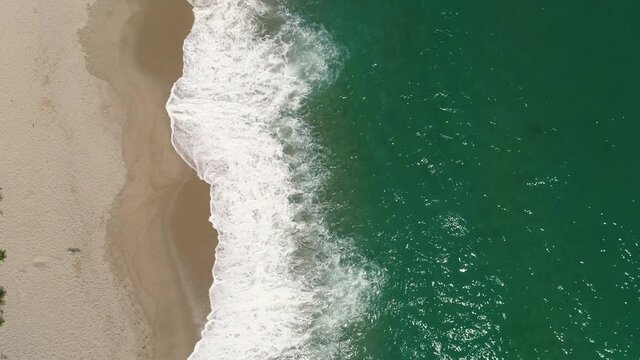 Aerial top view of ocean waves breaking on the beach sand, 4k video