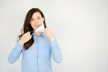 Young woman wants to put on a ffp2 protective mask. Cheerful business woman or teacher shows her ffp2 protective mask. Wearing mask in office. Person takes off the protective mask