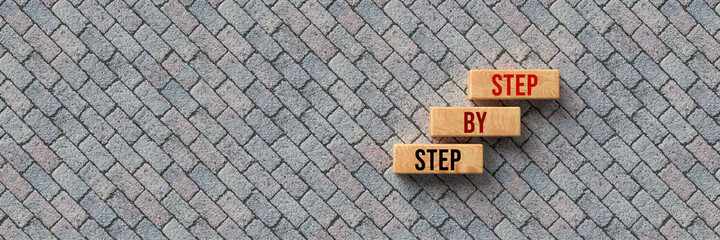 cubes with message STEP BY STEP on stone pavement background