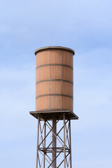 Wooden retro water tower against blue sky with light clouds