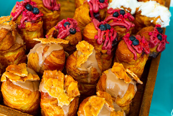 Fototapeta premium Wooden tray with assorted sweet cruffins topped with variety of creams .