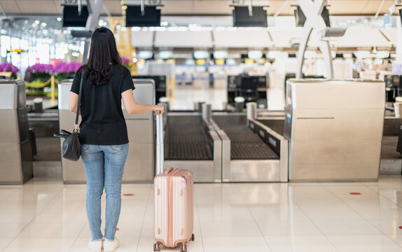 The back view of asian woman traveler carrying luggage prepare to check-in at the counter check in in the airport , Due to the Covid19 epidemic pandemic