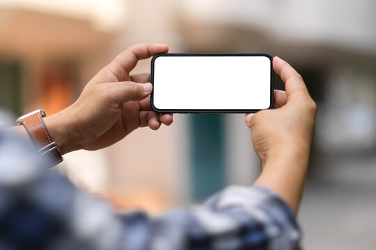 A Man Hands Holding Smartphone With Horizontal Clipping Path Screen In Blurred Background