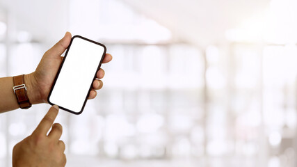 Hands using smartphone and showing mock-up screen to camera in blurred background