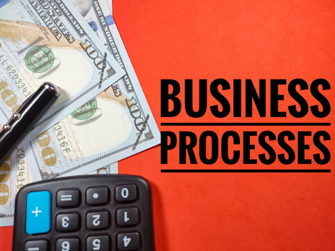 Business concept.Text BUSINESS PROCESSES with pen,banknote and calculator on red background.
