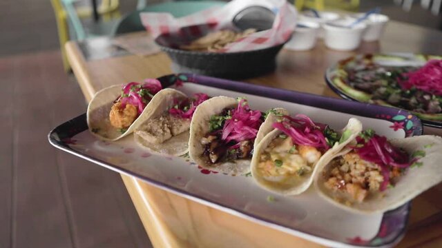 A handheld shot of a sampler platter of shrimp and fish tacos in a traditional sinaloan mexican restaurant.