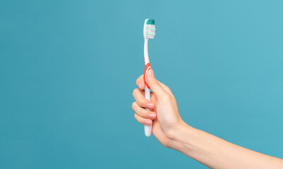 Hand​ holding​ toothbrushes on​​ blue background.​ Concept oral hygiene and health care.