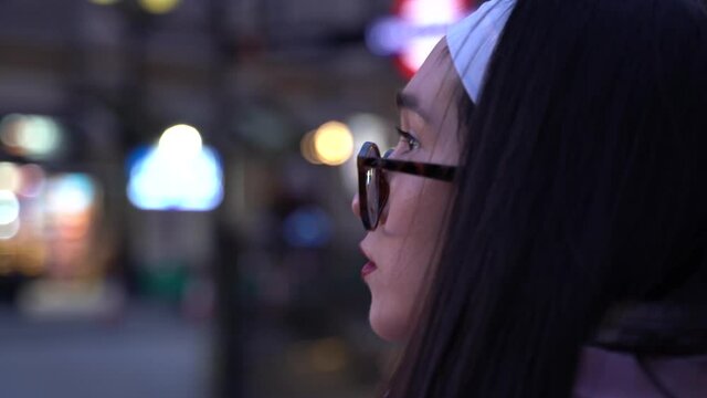 Close up of girl walking in streets alone at dusk, looking at her surroundings.