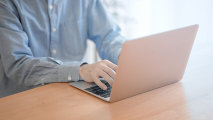 ノートパソコンでタイピングをするシニア男性