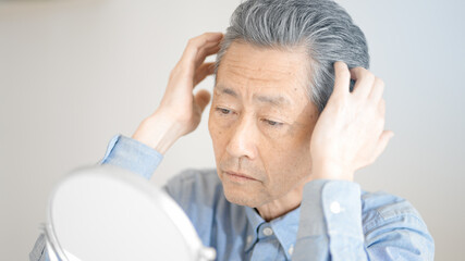 髪の毛を整えるシニア男性