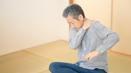 肩や首をマッサージするシニア男性