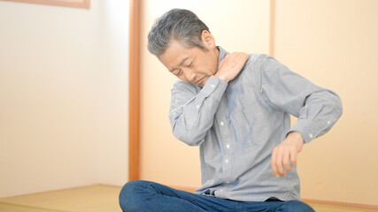 肩や首をマッサージするシニア男性