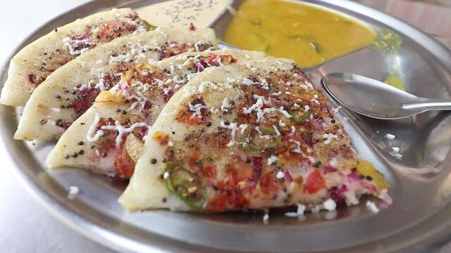 A street food seller serves Uttapam at his street food stall in Varanasi, India on 07 March 2021.