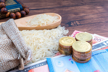 Holy Al Quran, Coins, Banknotes and Rice on wooden background. Zakat concept. Zakat is a form of alm-giving as a religious obligation