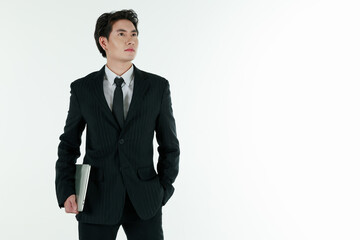 Portrait of self confidence young and handsome business Asian man in black suit holding notebook laptop computer with copy space studio shot isolated on white background