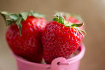 red delicious strawberries in a pink bucket