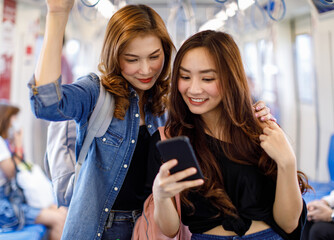 Content Asian women using smartphone together in train