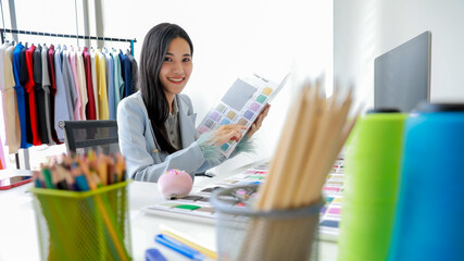 Young and beautiful Asian woman fashion designer working in design room with happiness