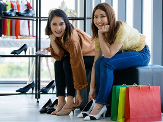 Fototapeta na wymiar Happy Asian girlfriends trying on shoes