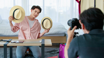 Young man shooting Asian blogger with hat