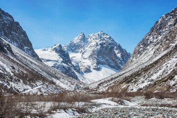 Idyllic winter landscape with hiking trail in the mountains. Rocks, snow and stones in mountain valley view. Mountain panorama.