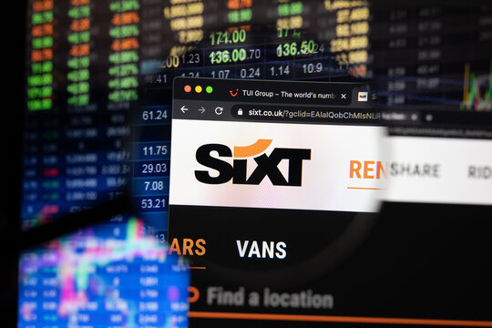 Sixt company logo on a website with blurry stock market developments in the background, seen on a computer screen through a magnifying glass