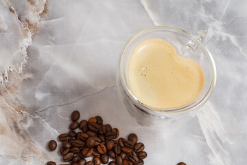 Cup of coffee and roasted coffee beans on kitchen desk.
