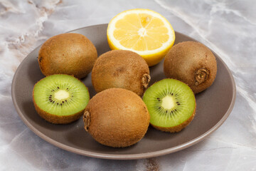 Obraz na płótnie Canvas Whole and sliced kiwi fruits and lemon on the stone table