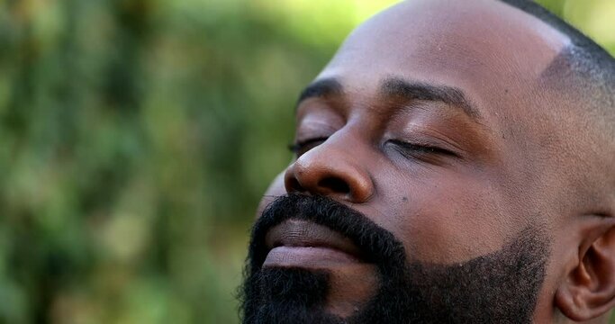 Positive African breathing fresh air outside, happy close-up face smiling