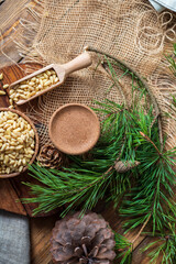 Peeled pine nuts in a bowl, pine cone on a cutting board, rough cloth next to it. View from above. Healthy food of forest gifts.