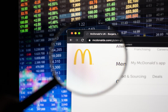 McDonalds company logo on a website with blurry stock market developments in the background, seen on a computer screen through a magnifying glass