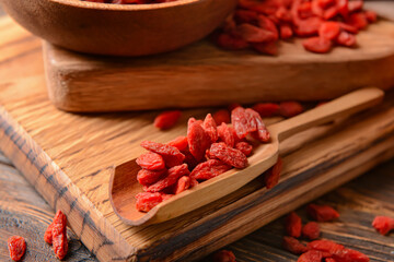 SCoop with dried goji berries on wooden background