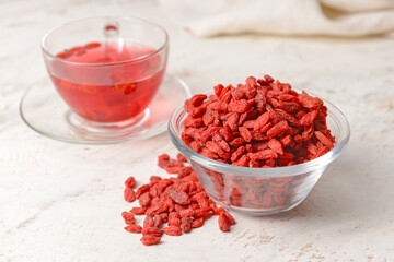 Bowl with dried goji berries on light background