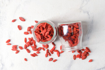 Jars with dried goji berries on light background