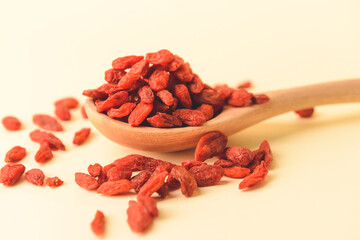 Spoon with dried goji berries on color background