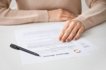 Woman with divorce decree and rings in lawyer's office, closeup