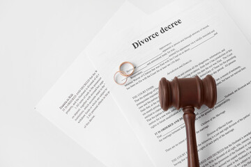 Divorce decree with judge's gavel and rings on white background