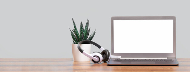 Laptop. Mockup screen and headphones on wooden desk and plain background banner. Distant learning. working from home, online courses or support minimal concept. Helpdesk or call center headset - obrazy, fototapety, plakaty