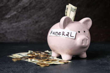 Piggy bank with money and word FUNERAL on dark background