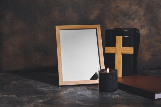 Blank photo frame and urn on dark background