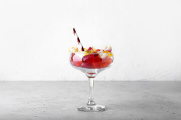 Glass of tasty jelly candies on light background