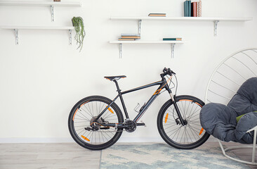 Modern bicycle near white wall in room