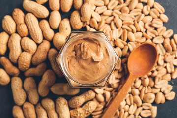 Jar with tasty peanut butter and nuts, closeup