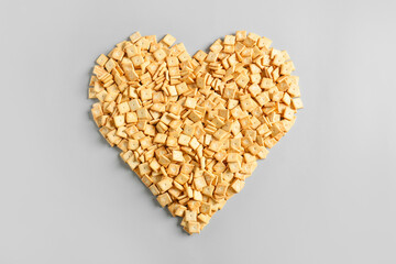 Heart made of tasty crackers on light background