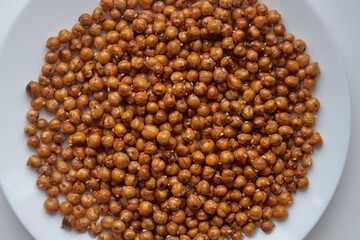 Top view of roasted chickpeas with sesame seeds on white plate. Delicious vegetarian food, healthy snack. Healthy food concept.